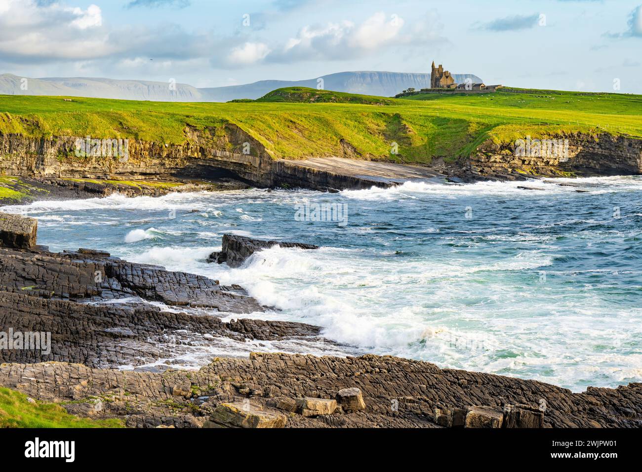 Famoso castello di Classiebawn nel pittoresco paesaggio di Mullaghmore Head. Spettacolare vista del tramonto con enormi onde che si infrangono a terra. Punto di firma di Wil Foto Stock