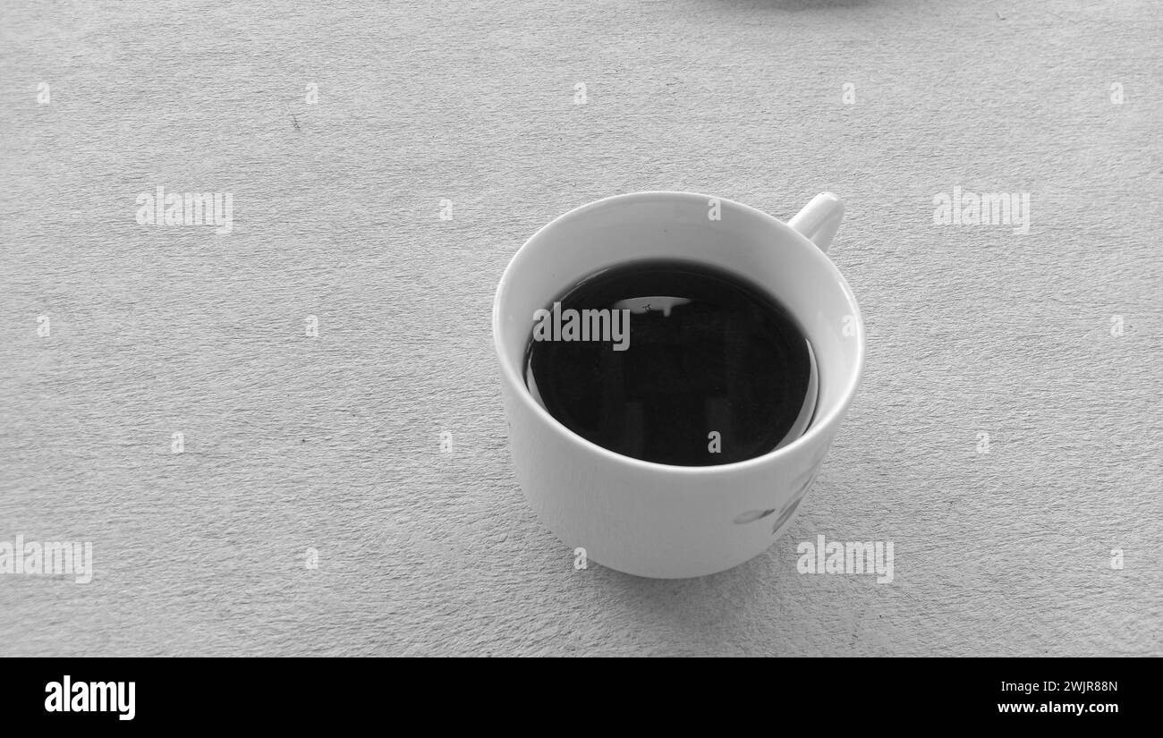 Foto di una tazza di caffè nera in una tazza bianca su sfondo bianco Foto Stock