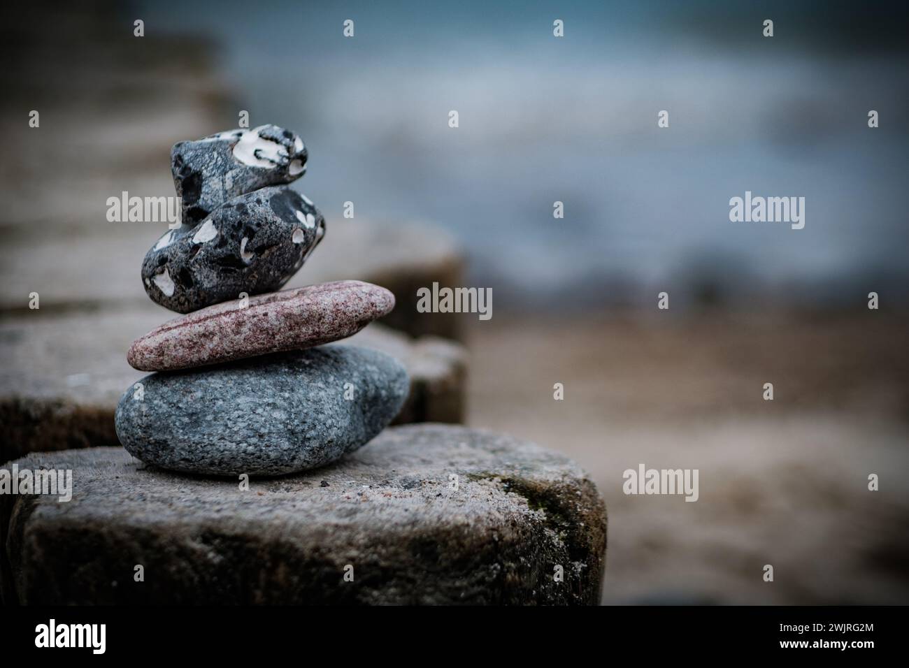 Una pila di pietre bilanciate su un tranquillo sfondo d'acqua che evoca calma. Foto Stock