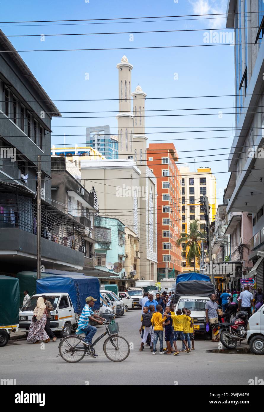 Un uomo passa davanti a un gruppo di ragazzi in questa visione generale della vita in una strada nel centro di Dar es Salaam, Tanzania. Foto Stock