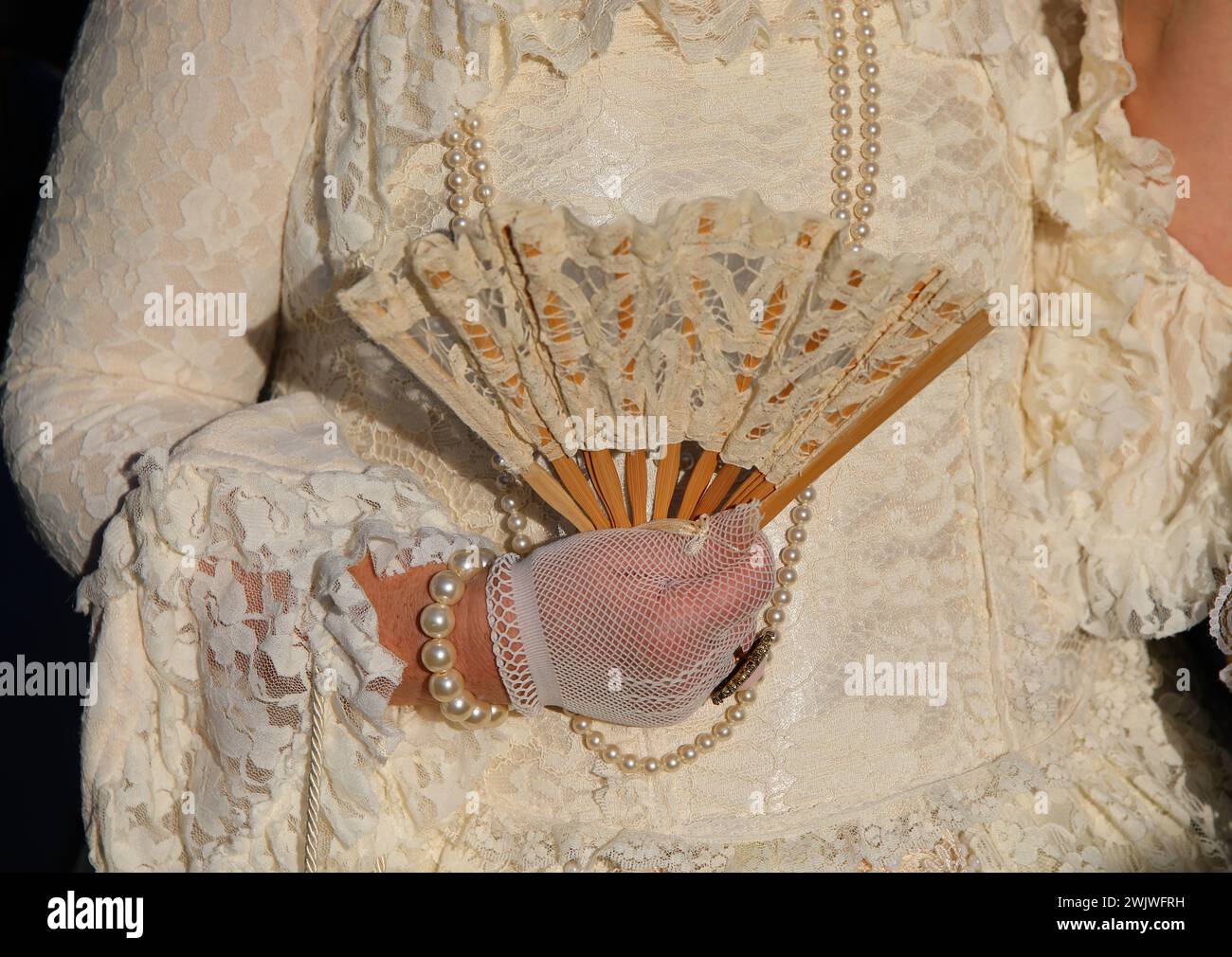 Nobildonna con lussuoso abito storico bianco avorio e un ventilatore con i guanti a mano durante la festa di Carnevale in maschera a Venezia Foto Stock