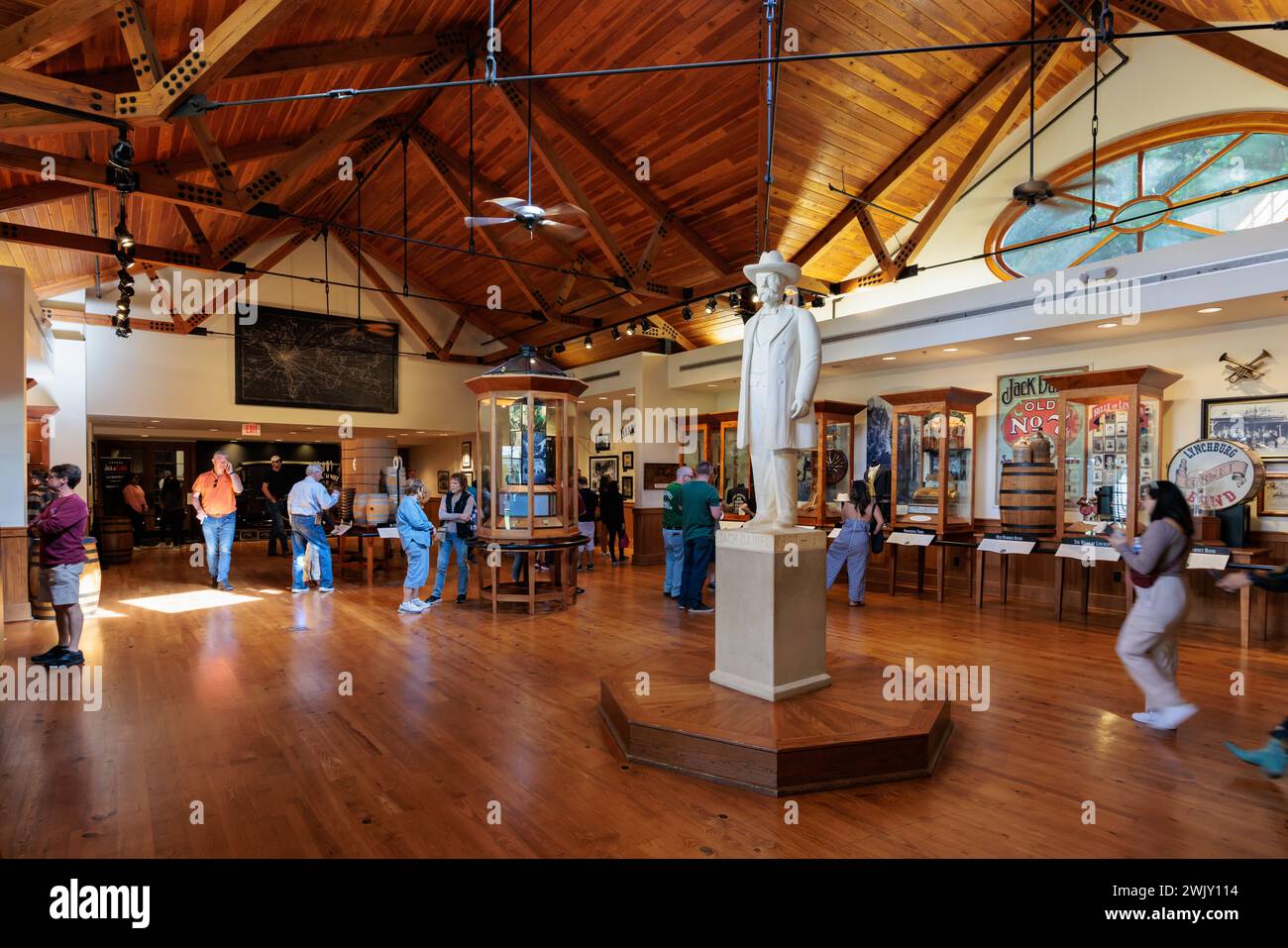 I visitatori osservano le esposizioni del museo intorno a una statua di Jack Daniel nel centro visitatori della distilleria Jack Daniel a Lynchburg, Tennessee Foto Stock