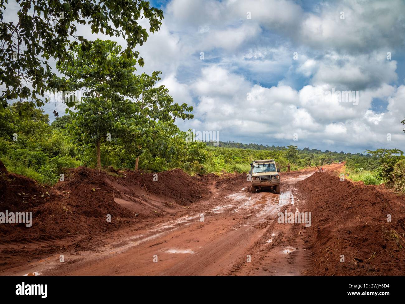 Un veicolo a 4 ruote motrici percorre una strada bagnata e fangosa di terra rossa vicino a Msanga, nella Tanzania rurale. Foto Stock