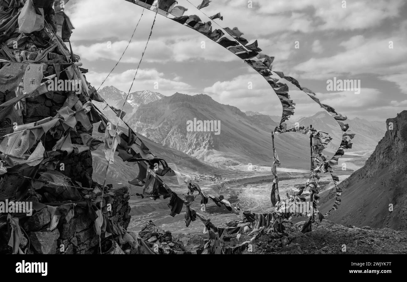 Le bandiere di preghiera buddiste soffiano nel vento che si affacciano sul fiume Spiti e sull'Himalaya sotto nuvole e cielo blu vicino a Kaza, Himachal Pradesh, India. Foto Stock