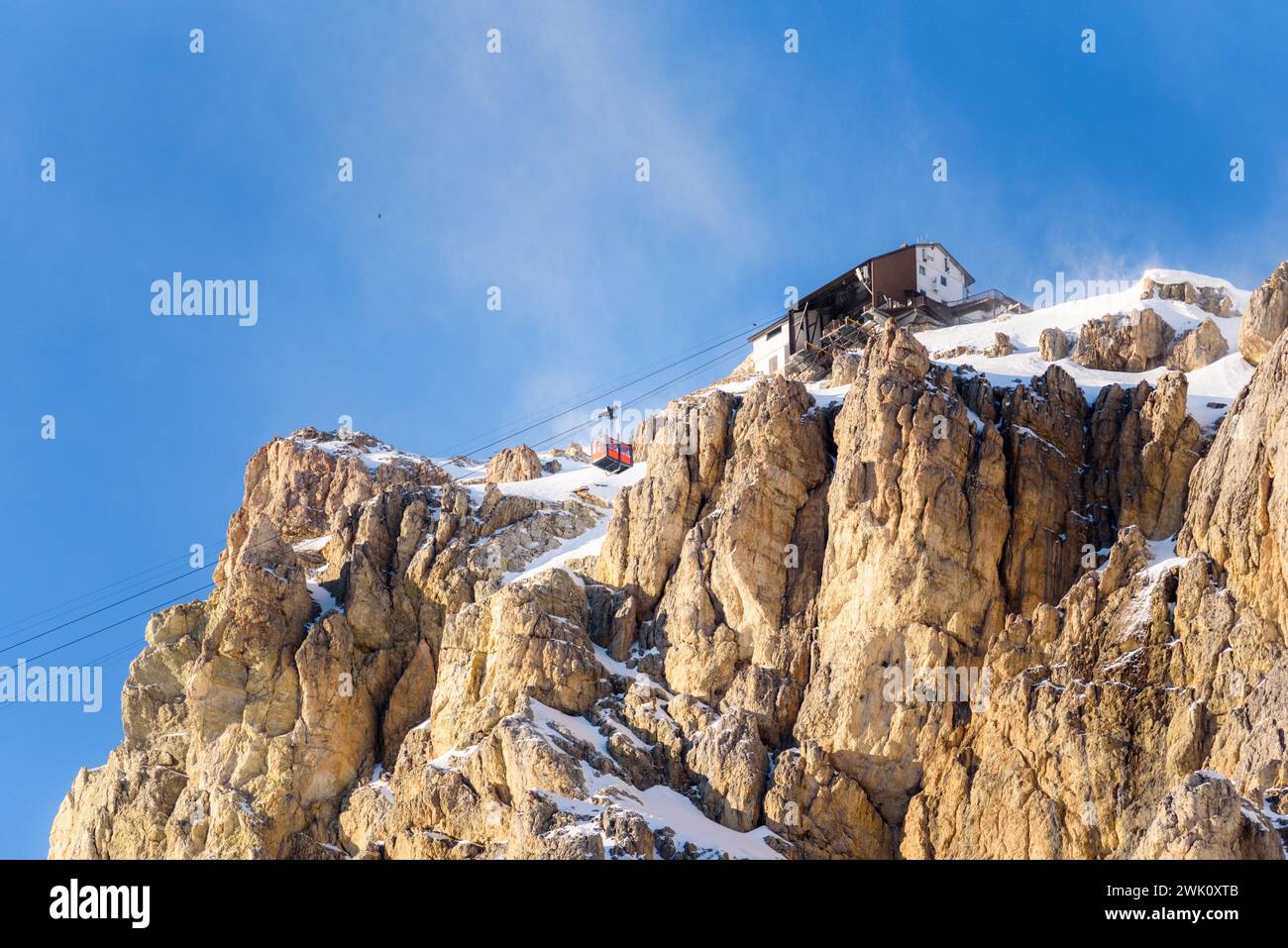 Cabina della funivia che si avvicina alla stazione superiore su una cima rocciosa innevata delle Alpi in una soleggiata giornata invernale Foto Stock