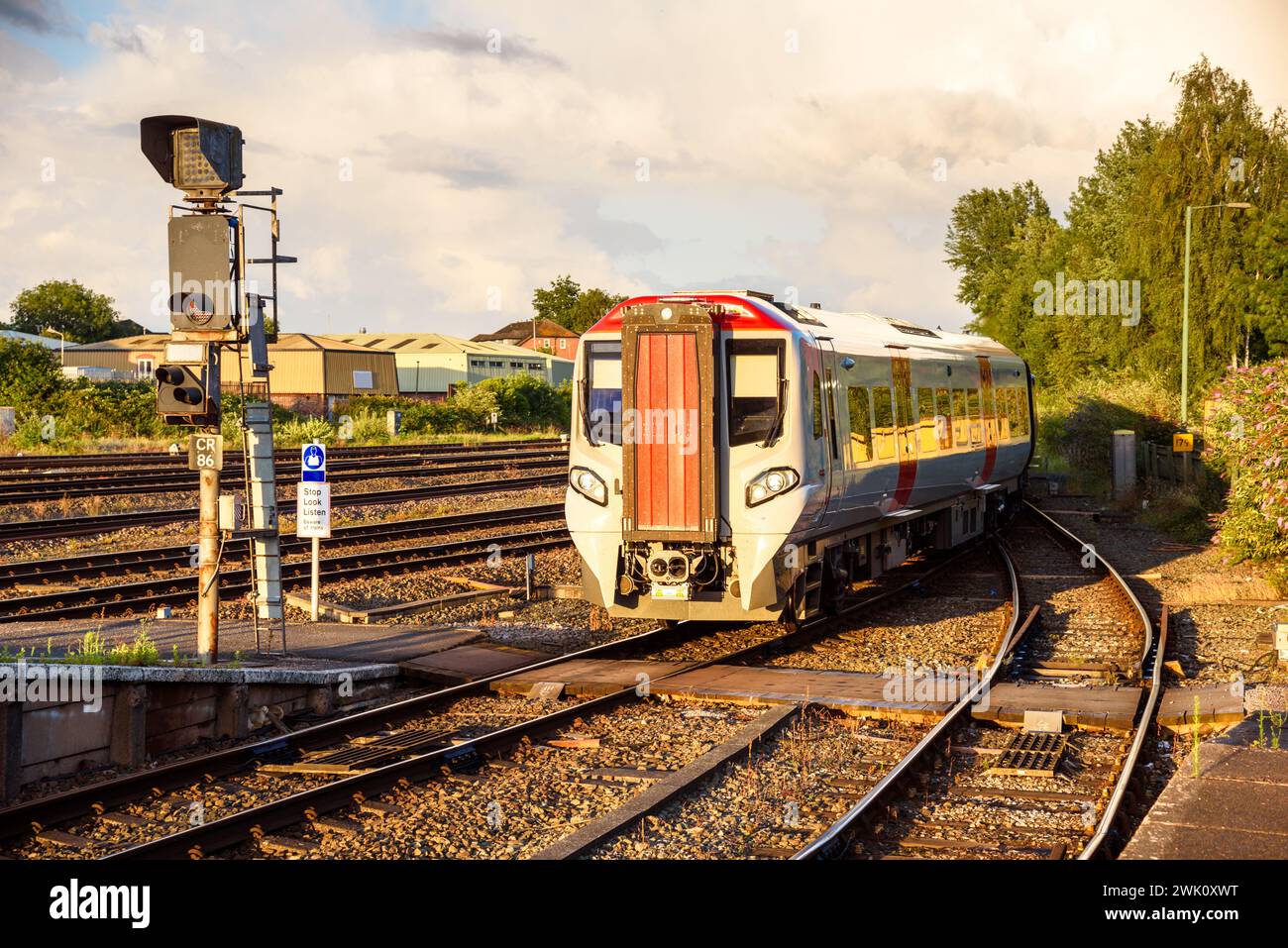 Treno diesel pendolare che arriva in una stazione al tramonto Foto Stock