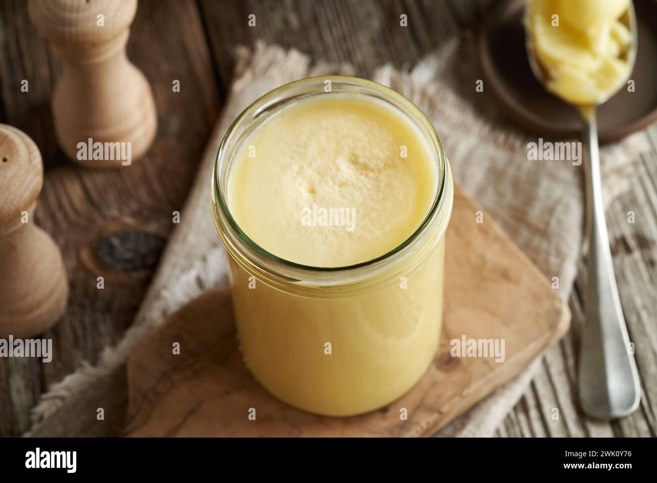 Un vaso di vetro di ghee o burro chiarificato su un tavolo Foto Stock