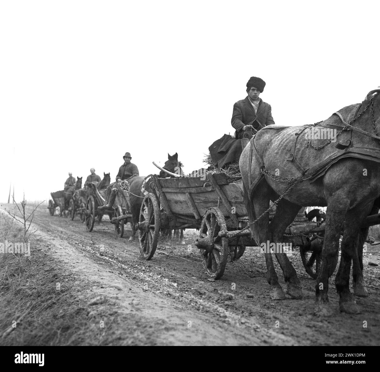 Repubblica Socialista di Romania, circa 1976. Contadini in carri trainati da cavalli su una strada di campagna fangosa. Foto Stock