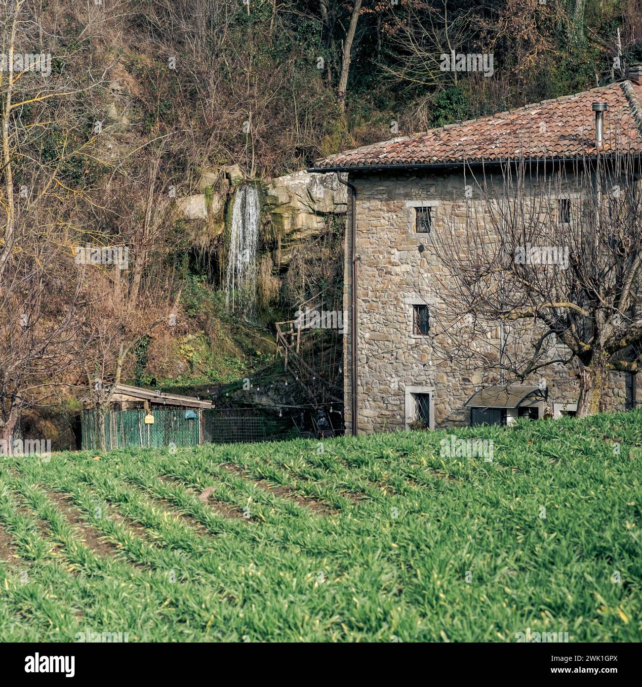 Antico mulino lungo una piccola e stretta valle con accanto una cascata, nella campagna bolognese. Roncastaldo, Loiano, Bologna, Emilia-Romagna, Foto Stock