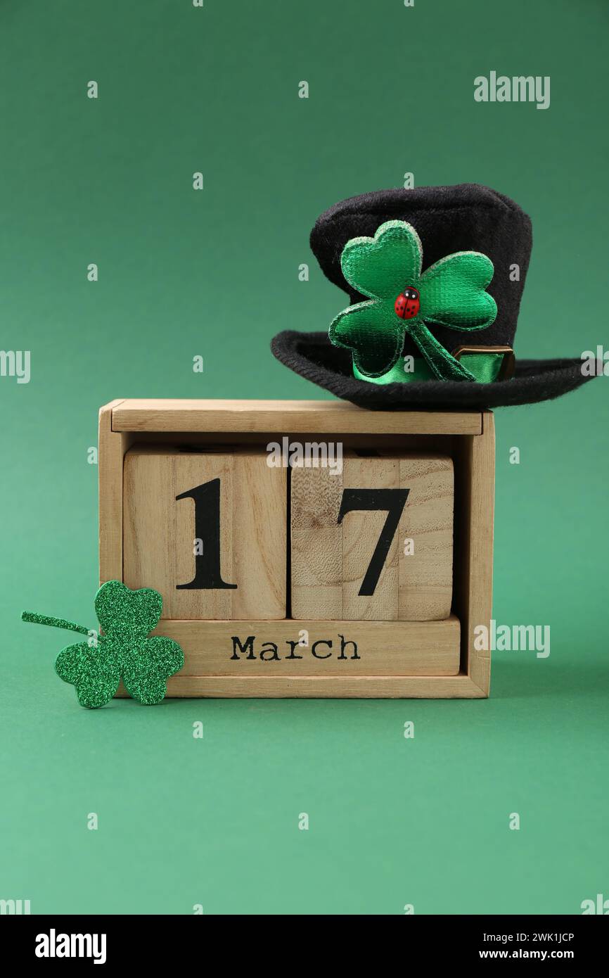 St Giorno di Patrick - 17 marzo. Calendario a blocchi, cappello di leprechaun e foglia di trifoglio decorativo su sfondo verde Foto Stock