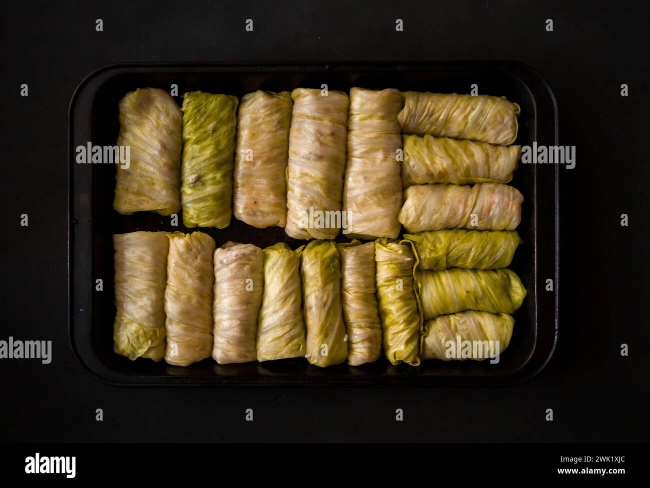 Rotoli di cavolo ripieni in una teglia da forno su sfondo nero. Messa a fuoco selettiva. Tonificato. Piatto tradizionale ucraino. Cucina dell'Europa orientale. vista dall'alto Foto Stock
