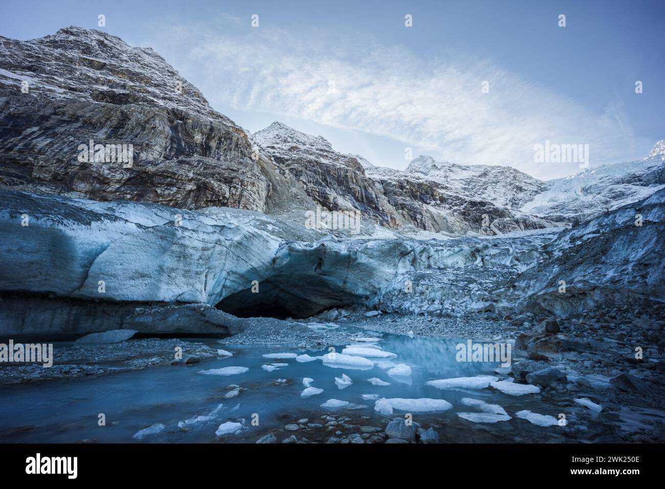 Vista del paesaggio invernale dell'ingresso di una grotta di ghiaccio circondata da montagne e piccoli iceberg Foto Stock