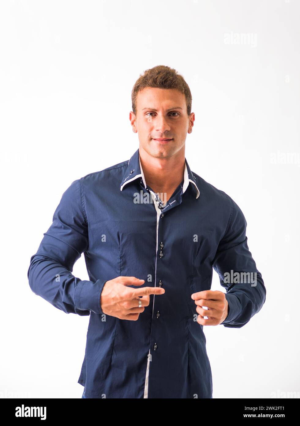 Un uomo che indossa una camicia blu sta puntando un oggetto fuori dalla fotocamera. Sembra che stia gestendo e dirigendo l'attenzione verso un punto specifico. Foto Stock