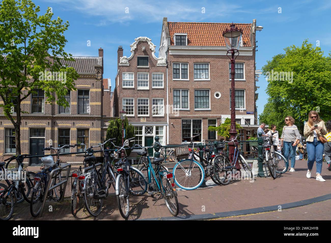 La gente cammina lungo le case sul canale all'angolo tra Prinsengracht e Lauriergracht ad Amsterdam. Foto Stock