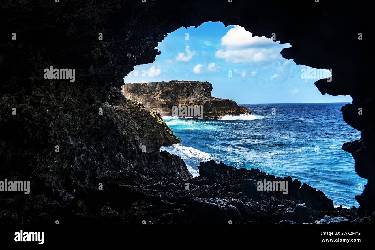 Una grotta alle Barbados che si affaccia sul mare e sulla costa frastagliata. Acqua in sospensione, interessante forma della crepa della grotta. Foto Stock