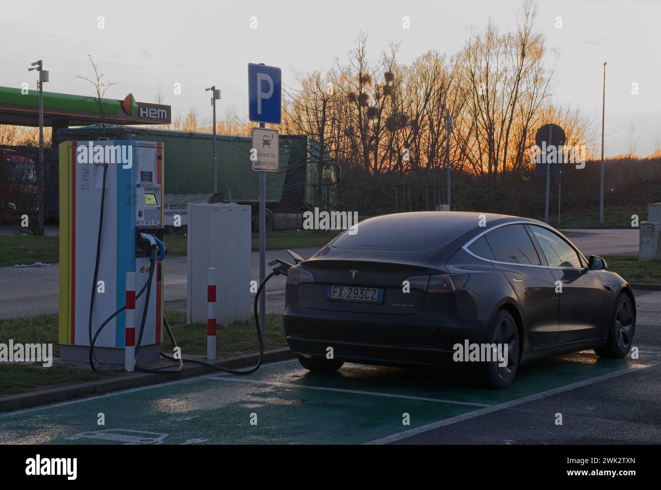 Rostock, Germania - 11 gennaio 2024: Un colpo statico di una ricarica a doppio motore Tesla Model 3 nera solida presso la stazione di ricarica CC del negozio Scandlines di confine in Foto Stock