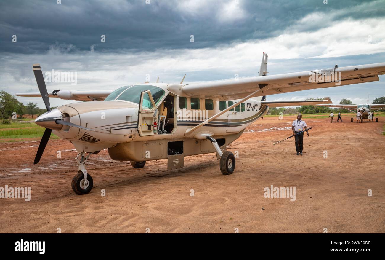 Un pilota porta un supporto di coda mentre effettua controlli pre-volo su un aereo leggero Cessna da 12 posti operato da Auric Air Services presso la pista di atterraggio di Mtemere a Nyerer Foto Stock