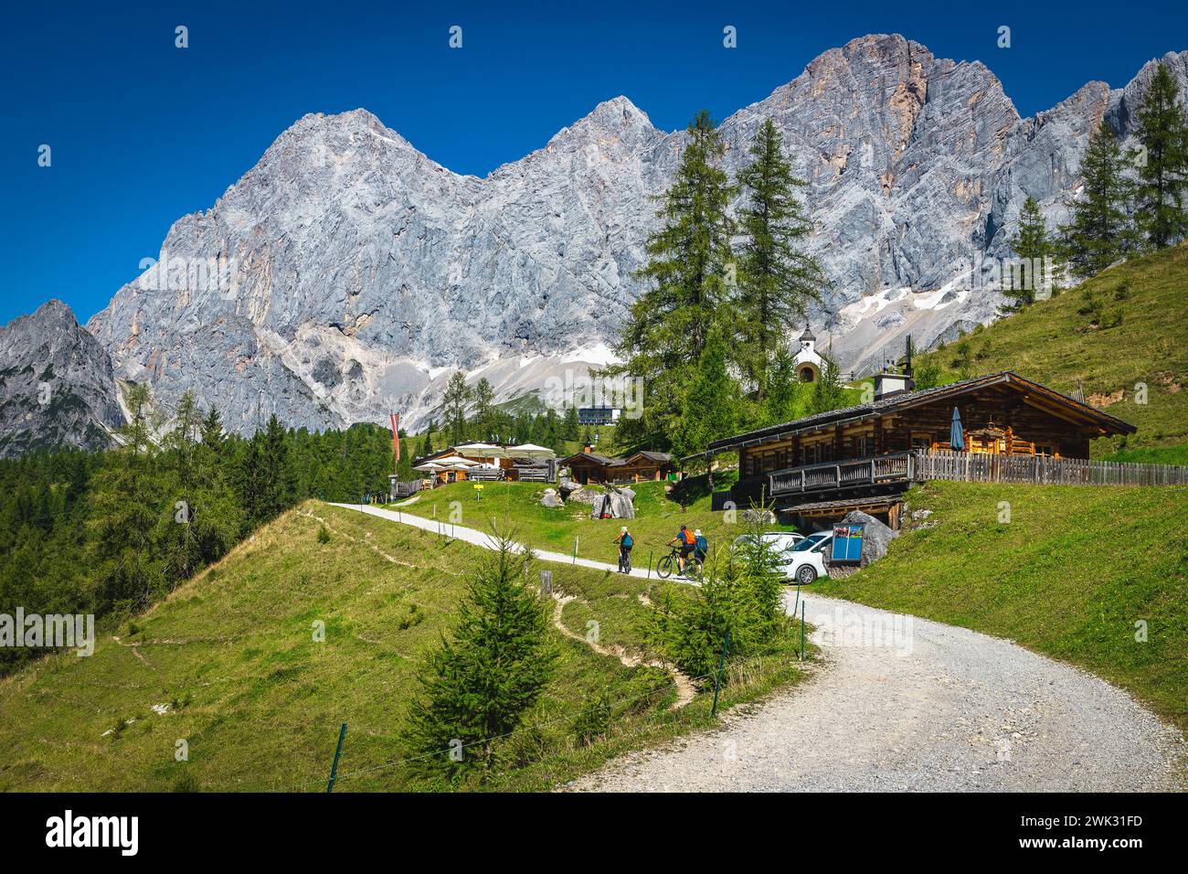 Splendida posizione per escursioni e viaggi, strada rurale e case in legno sul pendio verde alpino. Incredibili montagne di Dachstein sullo sfondo, Ramsau am Dach Foto Stock