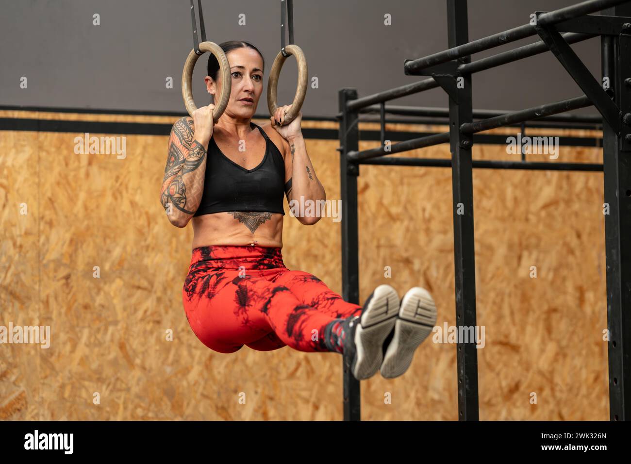 Donna che esegue esercizi di base appesa agli anelli olimpici Foto Stock