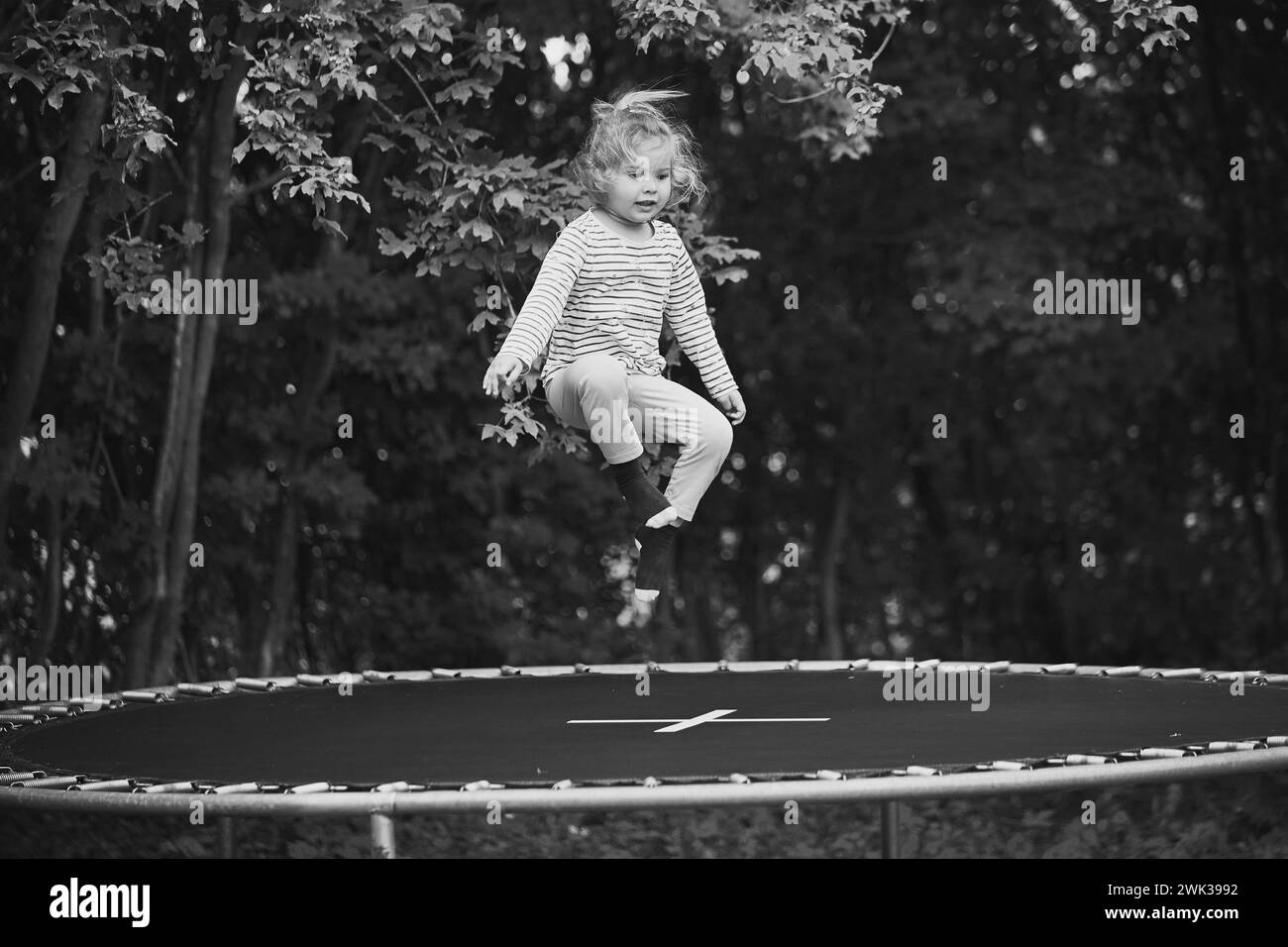 Bambino che salta su un trampolino nel giardino serale in Danimarca Foto Stock