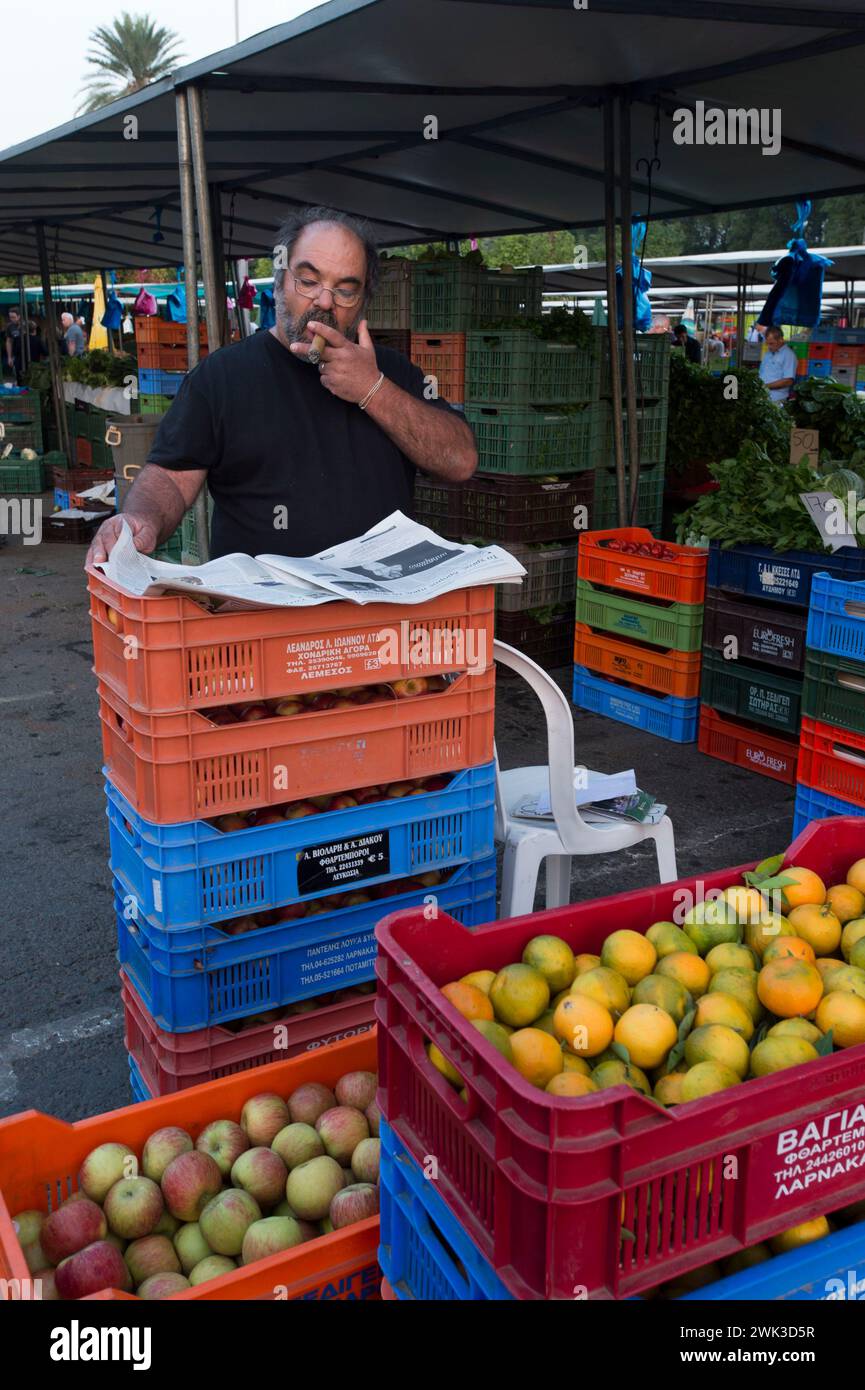 Giornata di mercato al Bastione di Constanza delle mura veneziane di Nicosia. Questo concessionario utilizza la pausa breve per studiare il giornale. Foto Stock