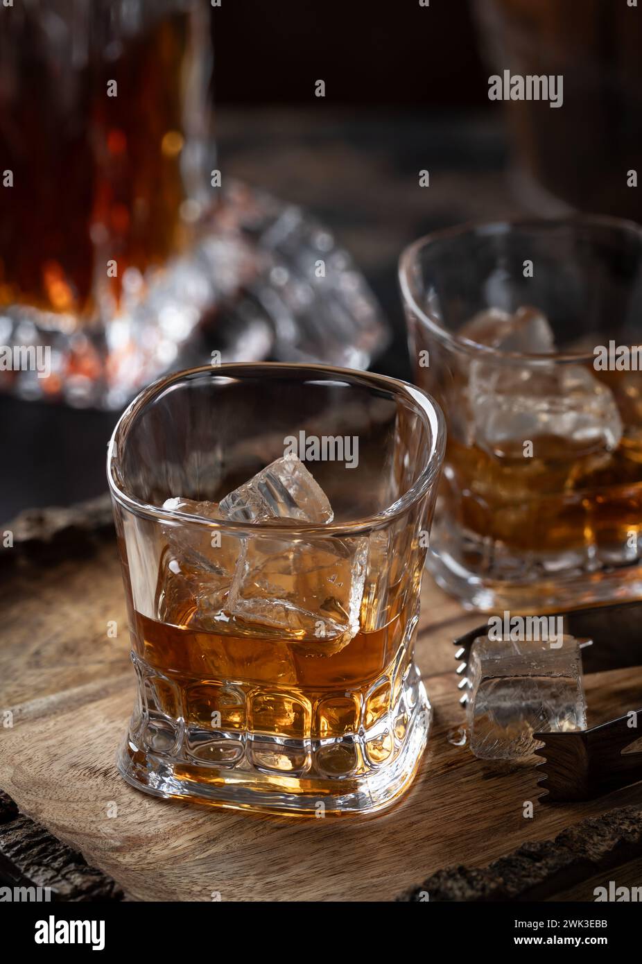 Due bicchieri di whisky con ghiaccio su vassoio in legno rustico con decanter in backgroound Foto Stock
