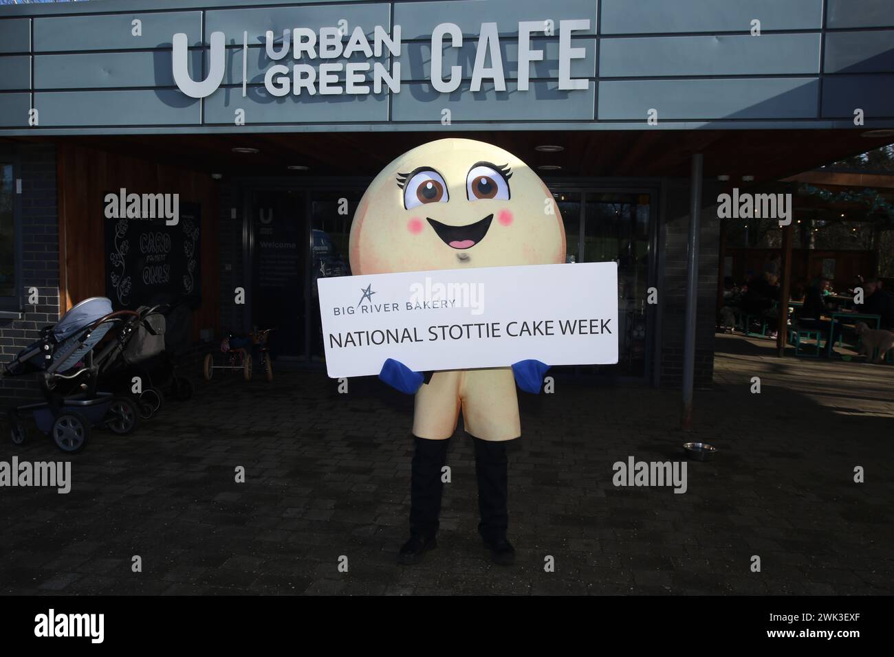 National Stottie Cake Week con la mascotte di Big River Bakery Scotty the Stottie che partecipa all'Urban Green Exhibition Park Café. La Big River Bakery, situata nel cuore di Shieldfield, Newcastle, ha recentemente annunciato una prima edizione culinaria: La National Stottie Cake Week. Una stottie è un tipo di pane rotondo, piatto e cotto sul fondo di un forno, che si traduce in una consistenza scrumptibilmente morbida ma gommosa. Prende il nome dalla parola Geordie «stot» – che significa «rimbalzare» – poiché tradizionalmente una stottie perfettamente cotta dovrebbe rimbalzare quando viene lasciata cadere. Newcastle upon Tyne, 18 febbraio 2024, credito: DEWAlamy Foto Stock