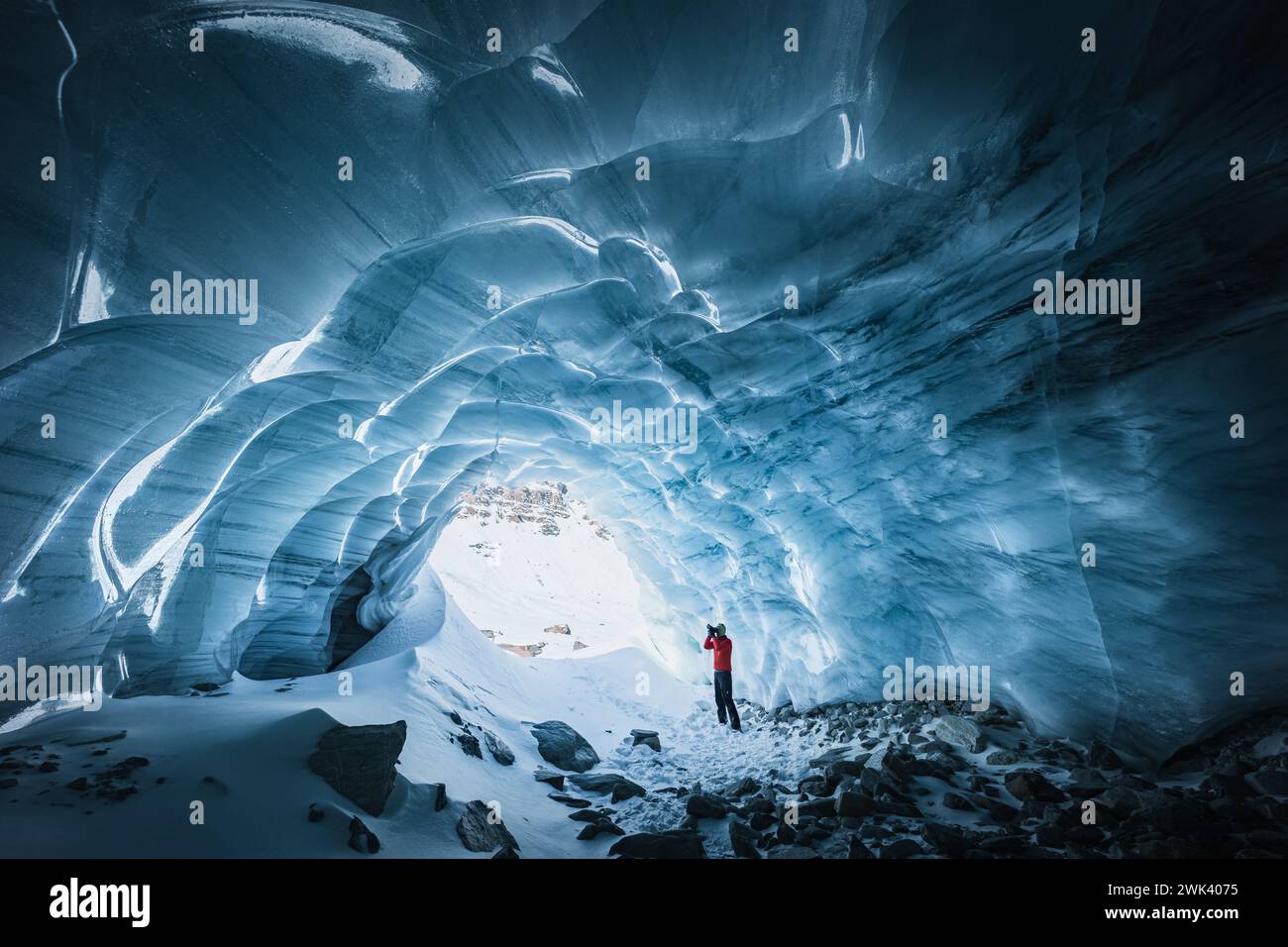 Vista del paesaggio di un fotografo che cattura la bellezza dell'interno di una grotta di ghiaccio testurizzata Foto Stock