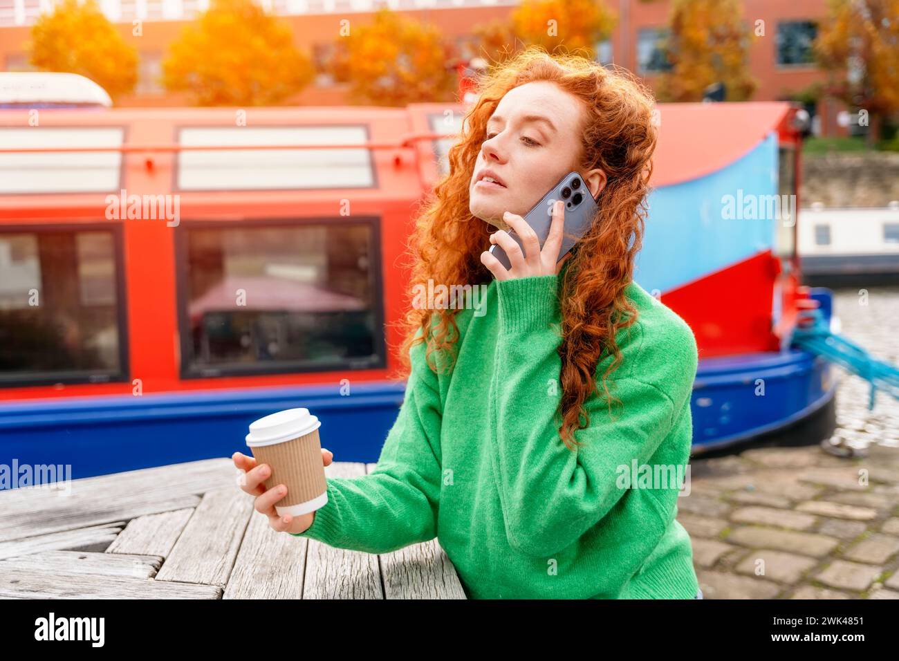 donna rossa in maglione verde che cammina sulle banchine, molo, seduto sulla panchina, guardando yacht, barca a vela, barca, parlare al telefono, bere caffè. LIF Foto Stock
