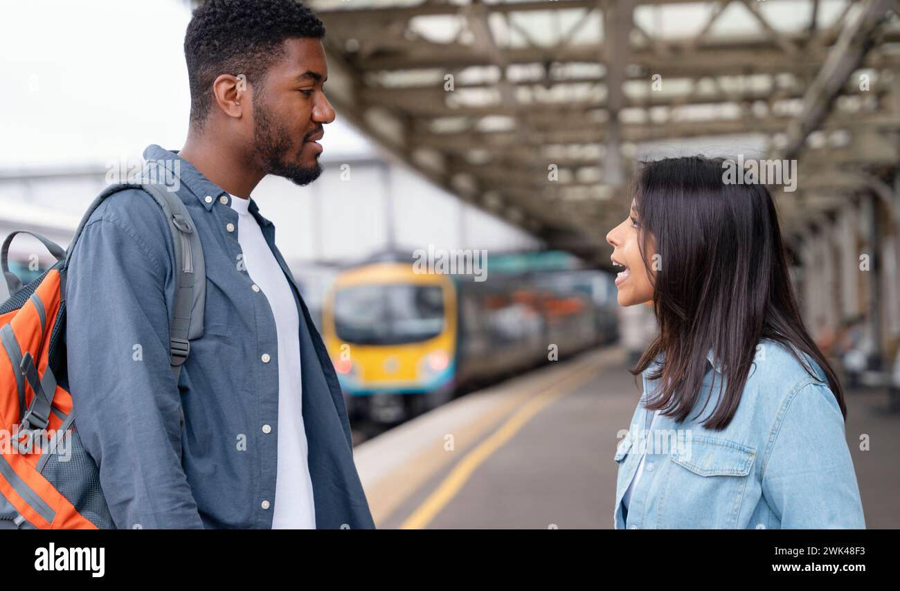 Una giovane coppia che giura e discute con ogni othe alla stazione ferroviaria sulla banchina il concetto di disaccordi in famiglia Foto Stock