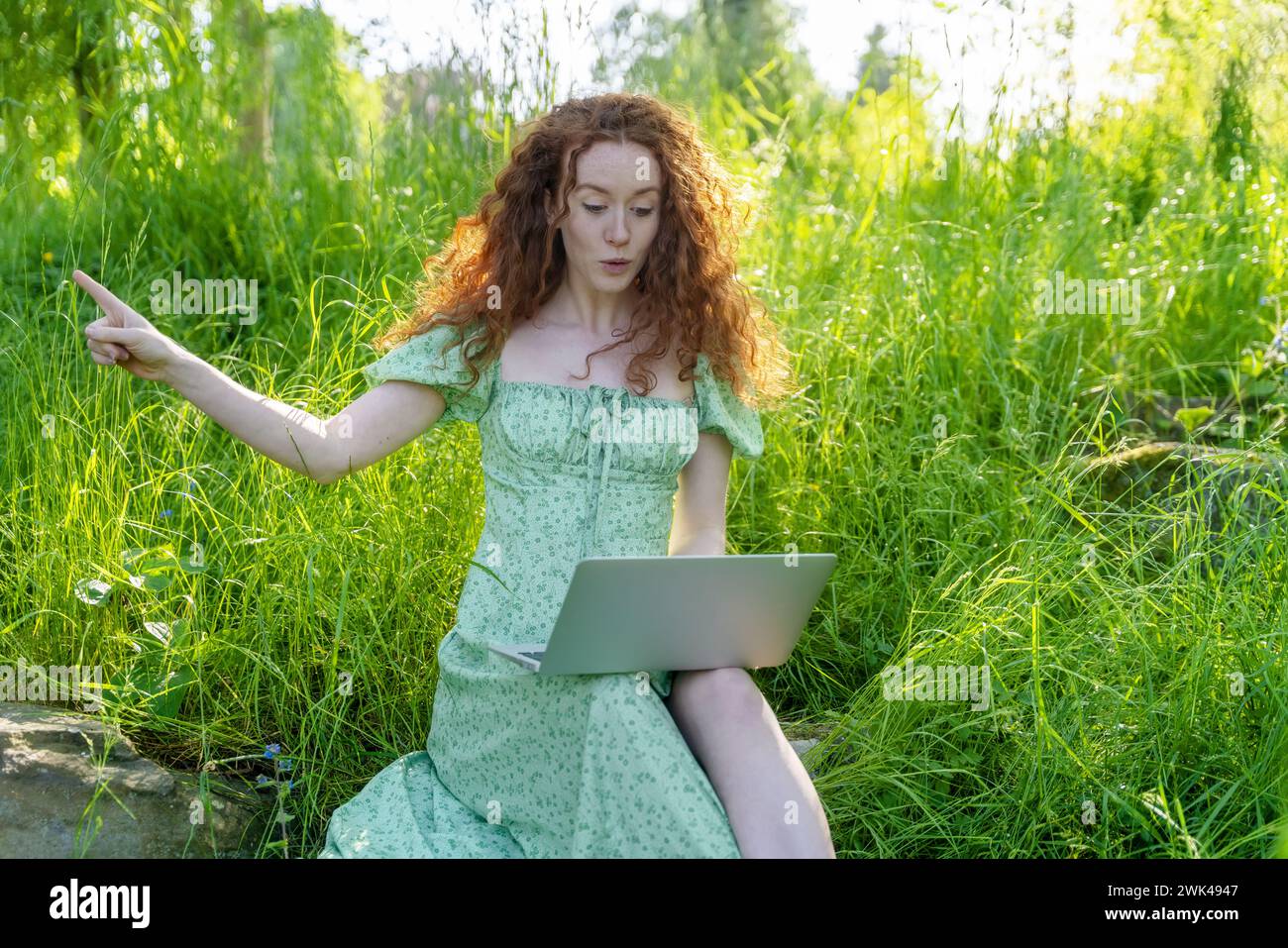 donna felice al parco in vacanza parlando, chiacchierando, insegnando, imparando, blogging al computer o al telefono con gli amici, . Internet Anywhere Foto Stock