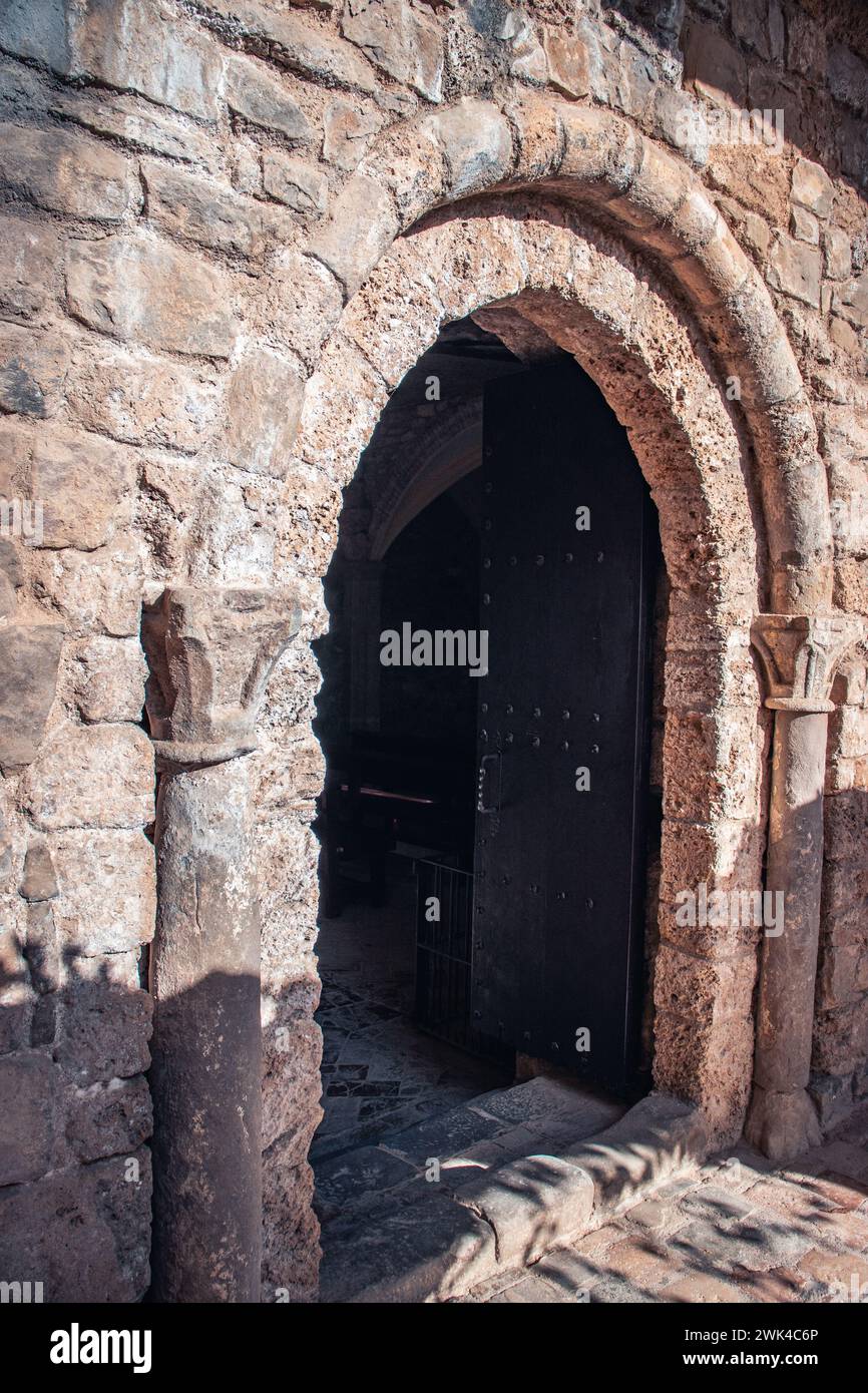 Porta nera che porta alla foto dell'antica chiesa. Fotografie murali in mattoni beige. Ingresso con due persiane. Foto del monastero di Sant Miquel del fai. Ciao Foto Stock