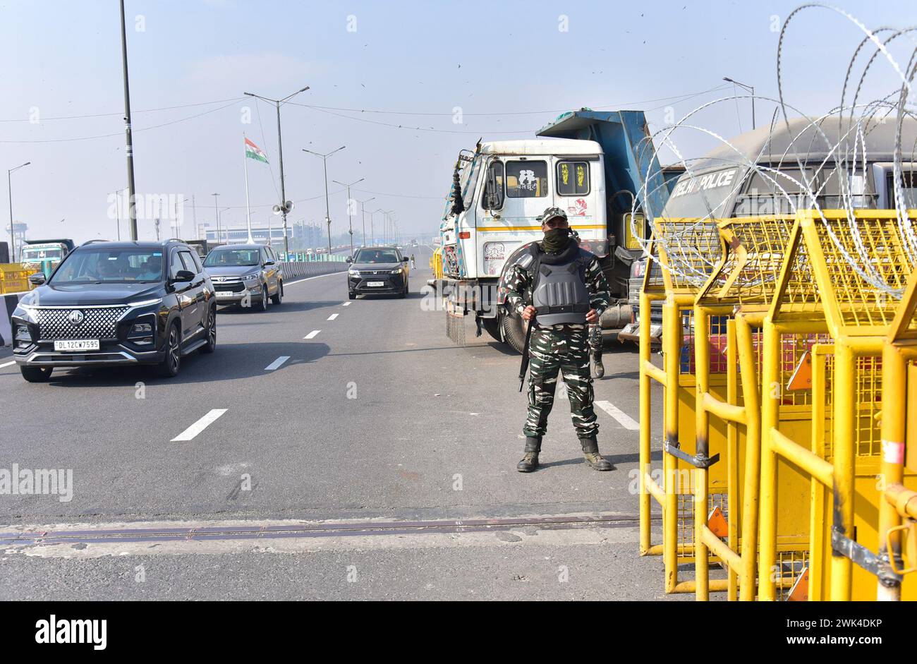 GHAZIABAD, INDIA - 18 FEBBRAIO: Il personale di polizia è in guardia accanto a una barriera per impedire agli agricoltori di protestare per chiedere prezzi minimi del raccolto di marciare verso la capitale nazionale al confine di Ghazipur, il 18 febbraio 2024 a Ghaziabad, India. Sono stati effettuati massicci dispiegamenti di polizia e personale paramilitare, oltre alla barricata multilivello, per sigillare i confini della capitale nazionale a Singhu, Tikri e Ghazipur, per impedire agli agricoltori che protestano di entrare in città durante la loro marcia prevista per il "Delhi Chalo". La polizia di Delhi ha anche imposto la sezione 144 della procedura penale Co Foto Stock