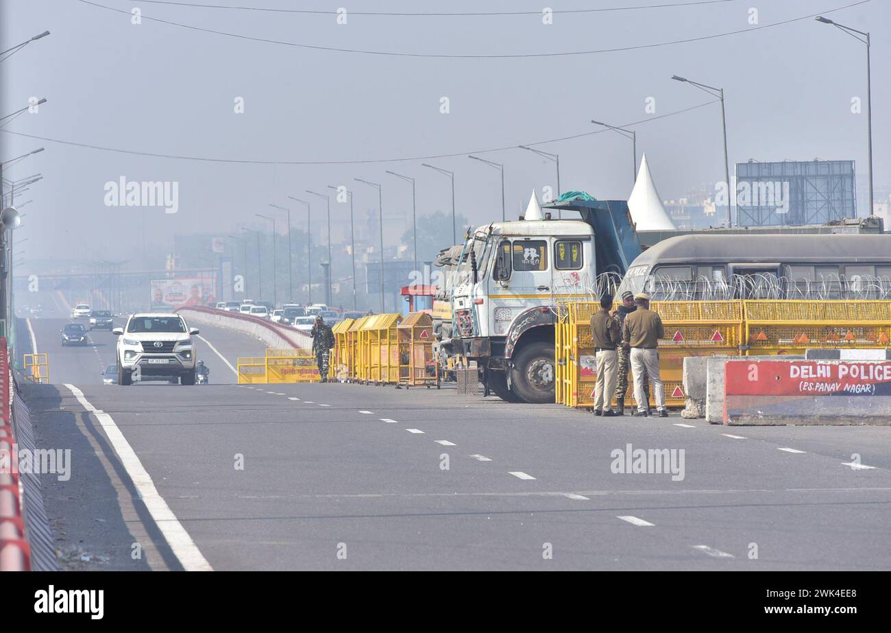 GHAZIABAD, INDIA - 18 FEBBRAIO: Il personale di polizia è in guardia accanto a una barriera per impedire agli agricoltori di protestare per chiedere prezzi minimi del raccolto di marciare verso la capitale nazionale al confine di Ghazipur, il 18 febbraio 2024 a Ghaziabad, India. Sono stati effettuati massicci dispiegamenti di polizia e personale paramilitare, oltre alla barricata multilivello, per sigillare i confini della capitale nazionale a Singhu, Tikri e Ghazipur, per impedire agli agricoltori che protestano di entrare in città durante la loro marcia prevista per il "Delhi Chalo". La polizia di Delhi ha anche imposto la sezione 144 della procedura penale Co Foto Stock