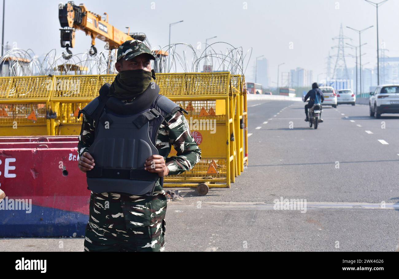 GHAZIABAD, INDIA - 18 FEBBRAIO: Il personale di polizia è in guardia accanto a una barriera per impedire agli agricoltori di protestare per chiedere prezzi minimi del raccolto di marciare verso la capitale nazionale al confine di Ghazipur, il 18 febbraio 2024 a Ghaziabad, India. Sono stati effettuati massicci dispiegamenti di polizia e personale paramilitare, oltre alla barricata multilivello, per sigillare i confini della capitale nazionale a Singhu, Tikri e Ghazipur, per impedire agli agricoltori che protestano di entrare in città durante la loro marcia prevista per il "Delhi Chalo". La polizia di Delhi ha anche imposto la sezione 144 della procedura penale Co Foto Stock