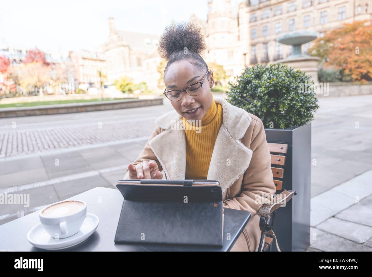 Studentessa africana e learning corso di formazione a distanza studiare lavorare in caffetteria. Giovane donna etnica che guarda il webinar online sull'istruzione utilizzando un notebook. Foto Stock
