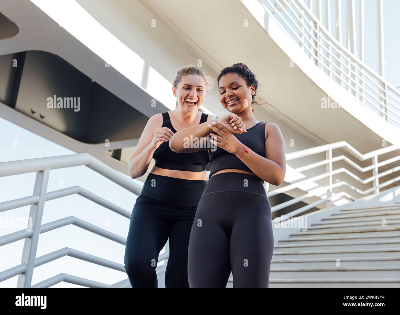 Due donne più grandi che guardano lo smartwatch mentre scendono sulle scale Foto Stock