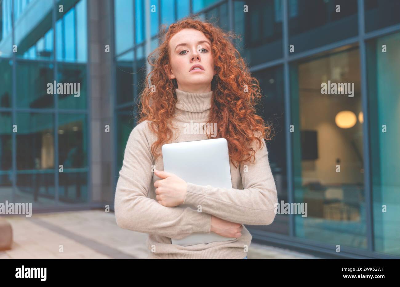 infelice donna rossa che regge un notebook e che è sotto shock dal nuovo in centro città Foto Stock