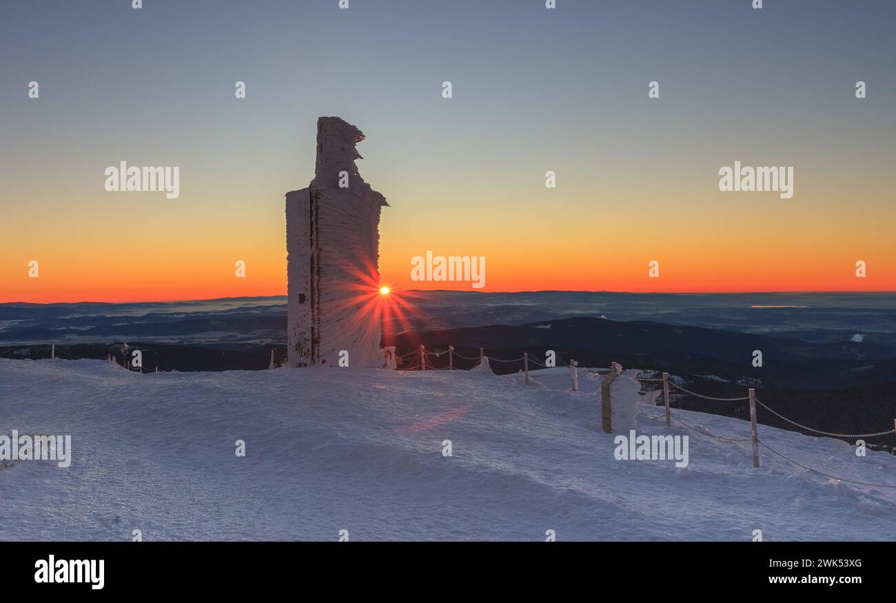 Ora dell'alba, colonna di pietra con quota di altezza 1603 m a snezka, montagna al confine tra Repubblica Ceca e Polonia, mattina d'inverno. Foto Stock
