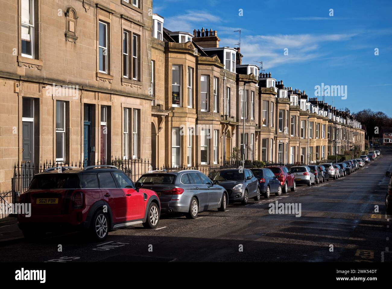 Fila di auto parcheggiate al di fuori delle case a schiera nella zona di Inverleith di Edimburgo, Scozia, Regno Unito. Foto Stock