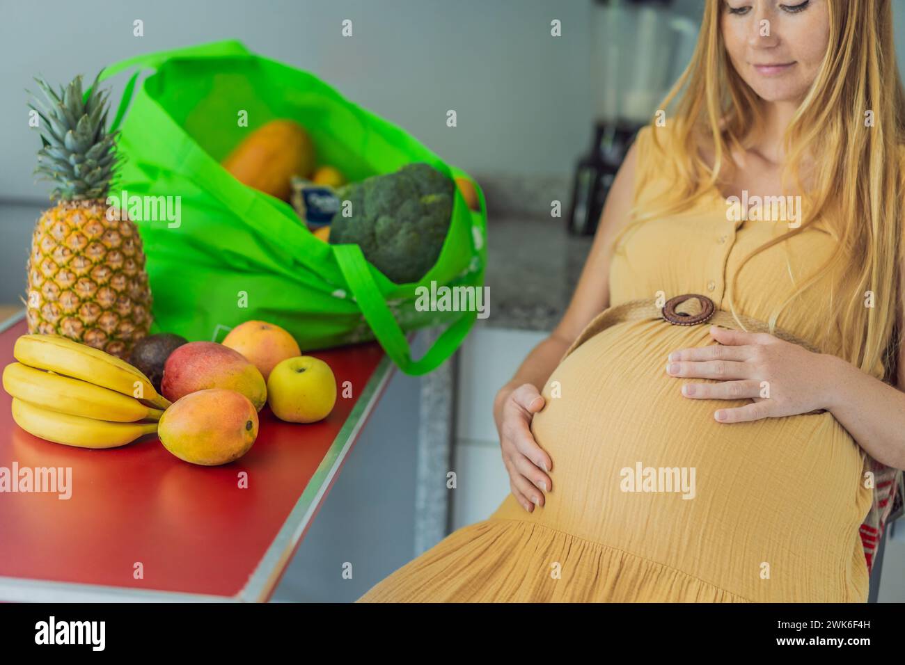 Esausta ma resiliente, una donna incinta prova stanchezza dopo aver portato a casa una grossa borsa di generi alimentari, dimostrando la sua dedizione a fornire Foto Stock