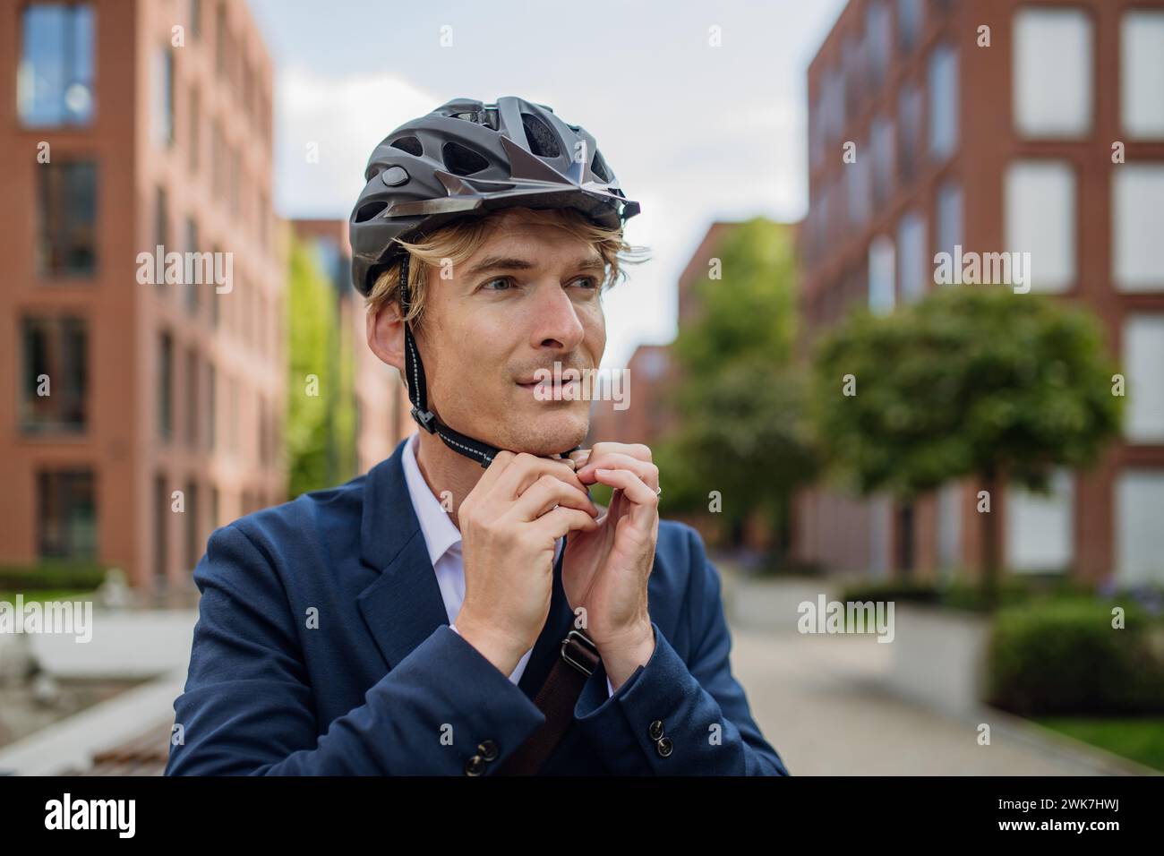 Bell'uomo di mezza età che viaggia per la città in bicicletta in tuta nera. Uomo pendolare di città che viaggia dal lavoro in bicicletta dopo una lunga giornata di lavoro. Foto Stock