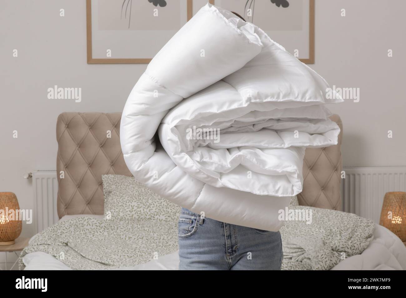 Donna che tiene un mucchio di soffici piumoni e cuscini piegati bianchi a casa nella sua camera da letto, stile di vita domestico accogliente, pulizia casalinga, riordino la camera da letto Foto Stock