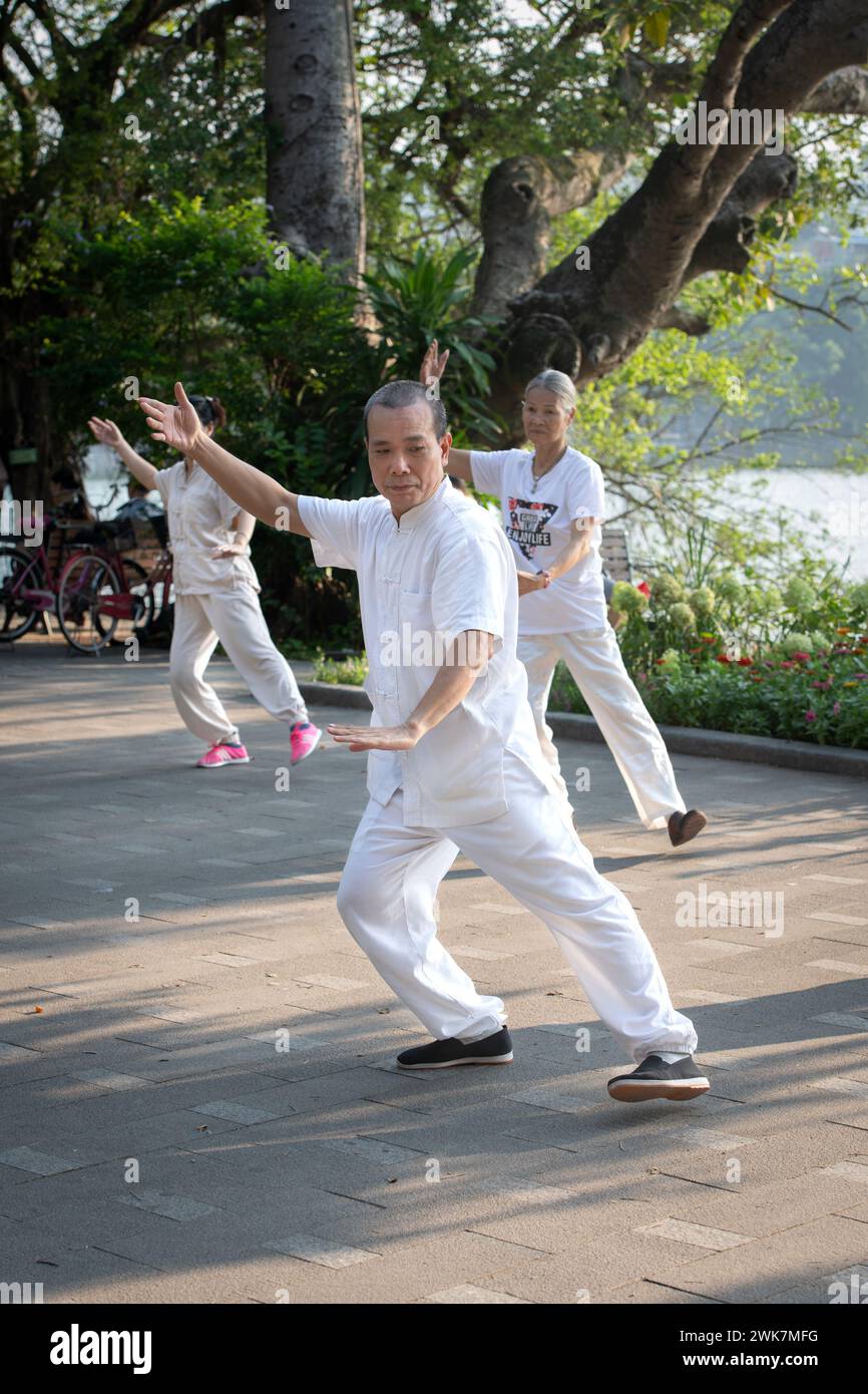 Gente che fa tai chi di mattina presto intorno al lago Hoan Kiem ad Hanoi, Vietnam Foto Stock