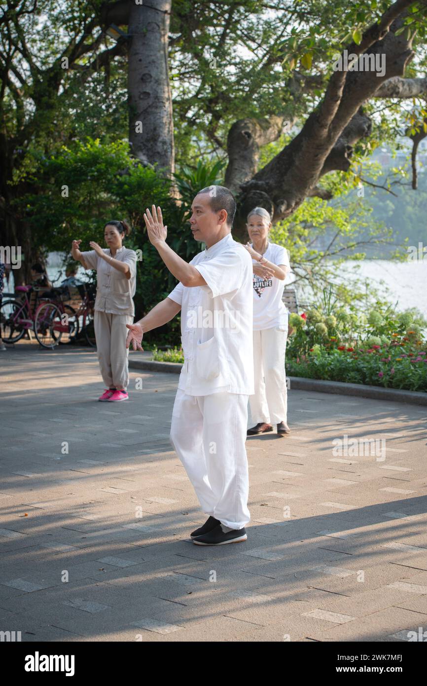 Gente che fa tai chi di mattina presto intorno al lago Hoan Kiem ad Hanoi, Vietnam Foto Stock