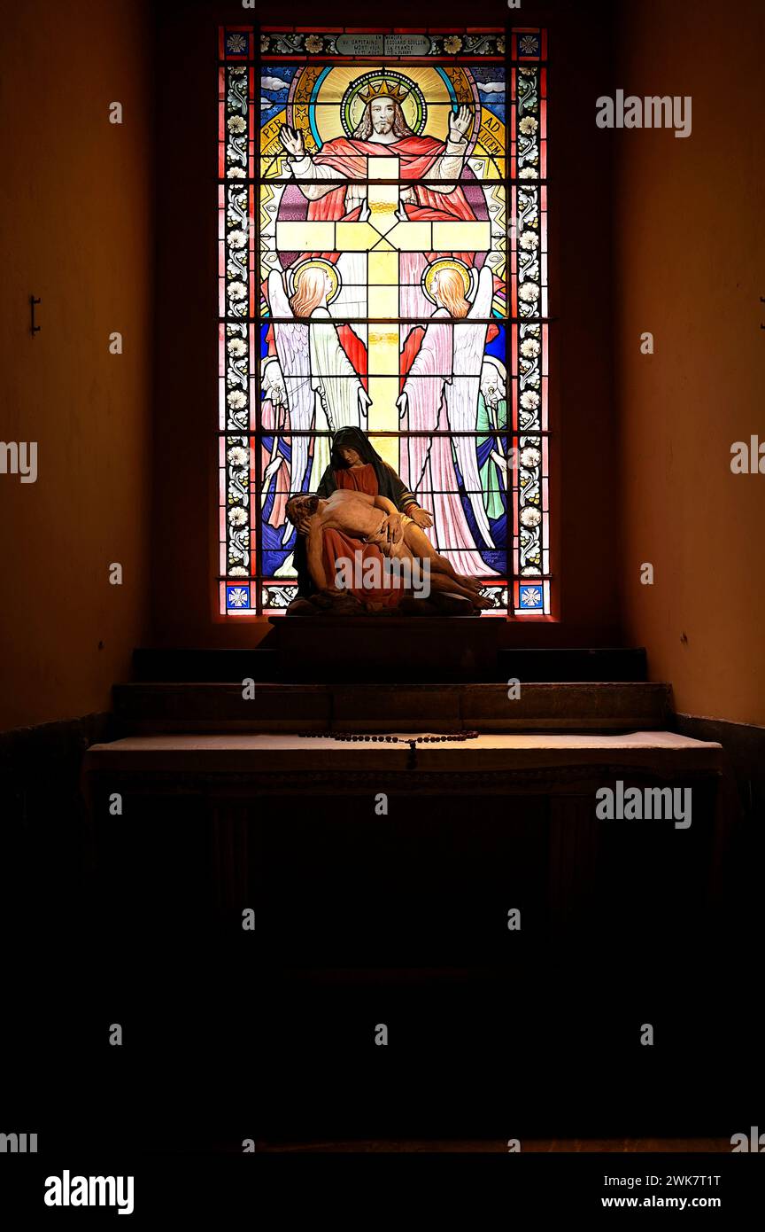 Statua della pietà, raffigurante la Vergine Maria che contempla il corpo di suo figlio, con vetrate colorate del Cristo risorto e croce sorretta da due angeli Foto Stock