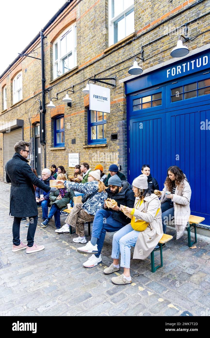 Persone sedute fuori Fortitude Bakehouse a mangiare panini e pasticceria, Londra, Inghilterra Foto Stock