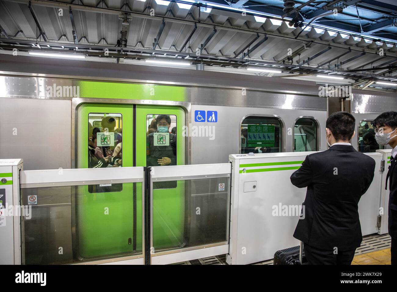 Treno affollato Tokyo, Giappone come pendolare maschile attende che le porte si aprano e la barriera porta si solleva, Asia, 2023 Foto Stock