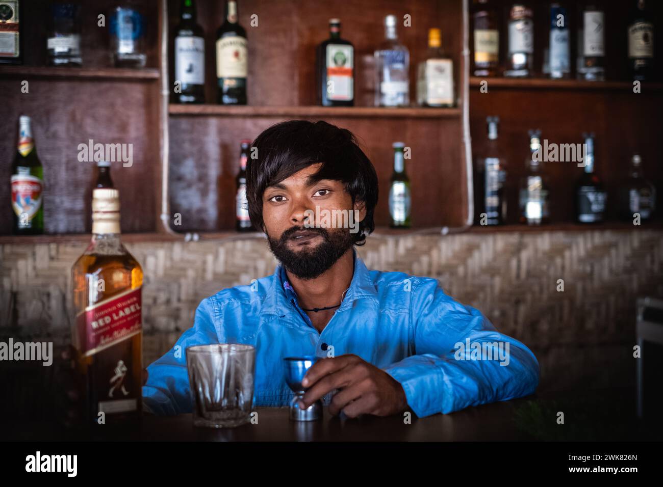 Bevande alcoliche, persone e concetto di professione - barman indiano a Goa India. Il bar si sta preparando a versare un drink nel bicchiere. Foto Stock