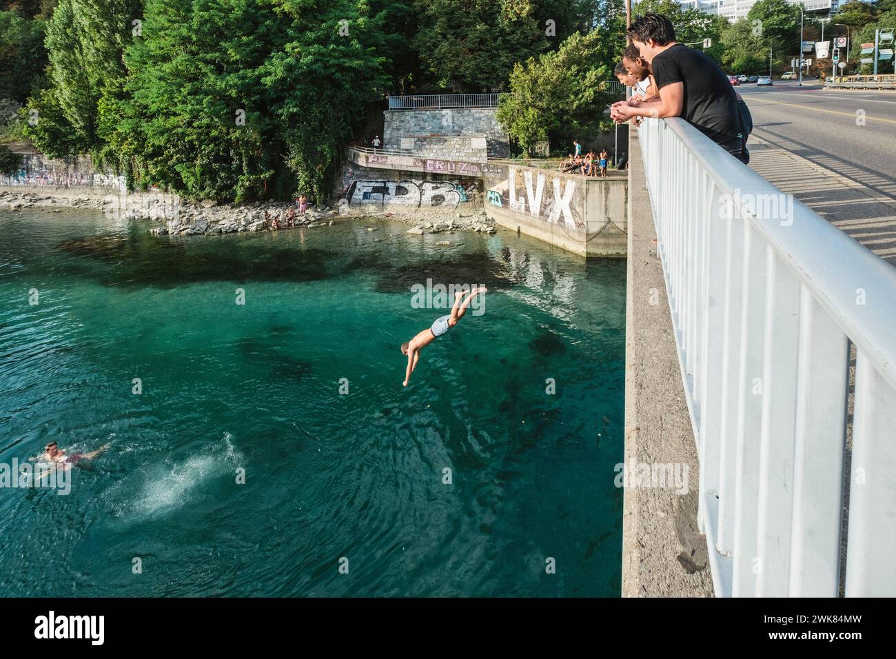 Scena estiva di un uomo che salta da un ponte nel fiume Rodano a Ginevra, Svizzera Foto Stock